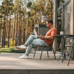 A young man with a laptop sitting outside and working online